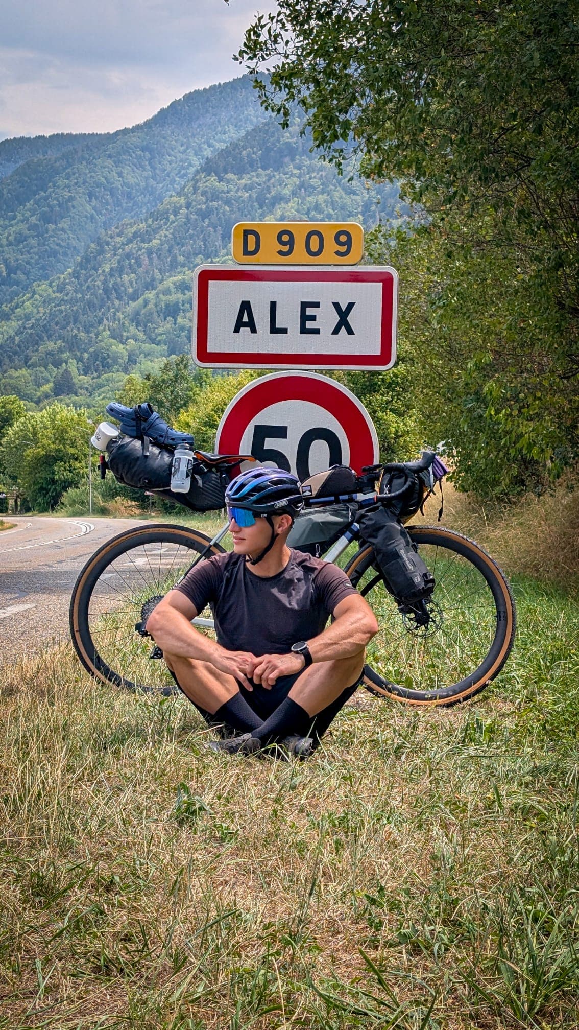 Pauză de bikepacking lângă bicicletă și un indicator rutier cu numele Alex
